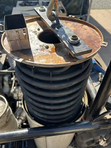 Lifting damaged heating coil out of Nilfisk Contractor diesel pressure washer boiler during repair.